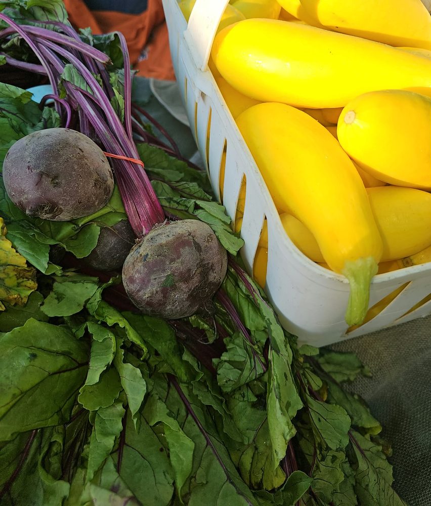 Beets with their greens beside yellow squash